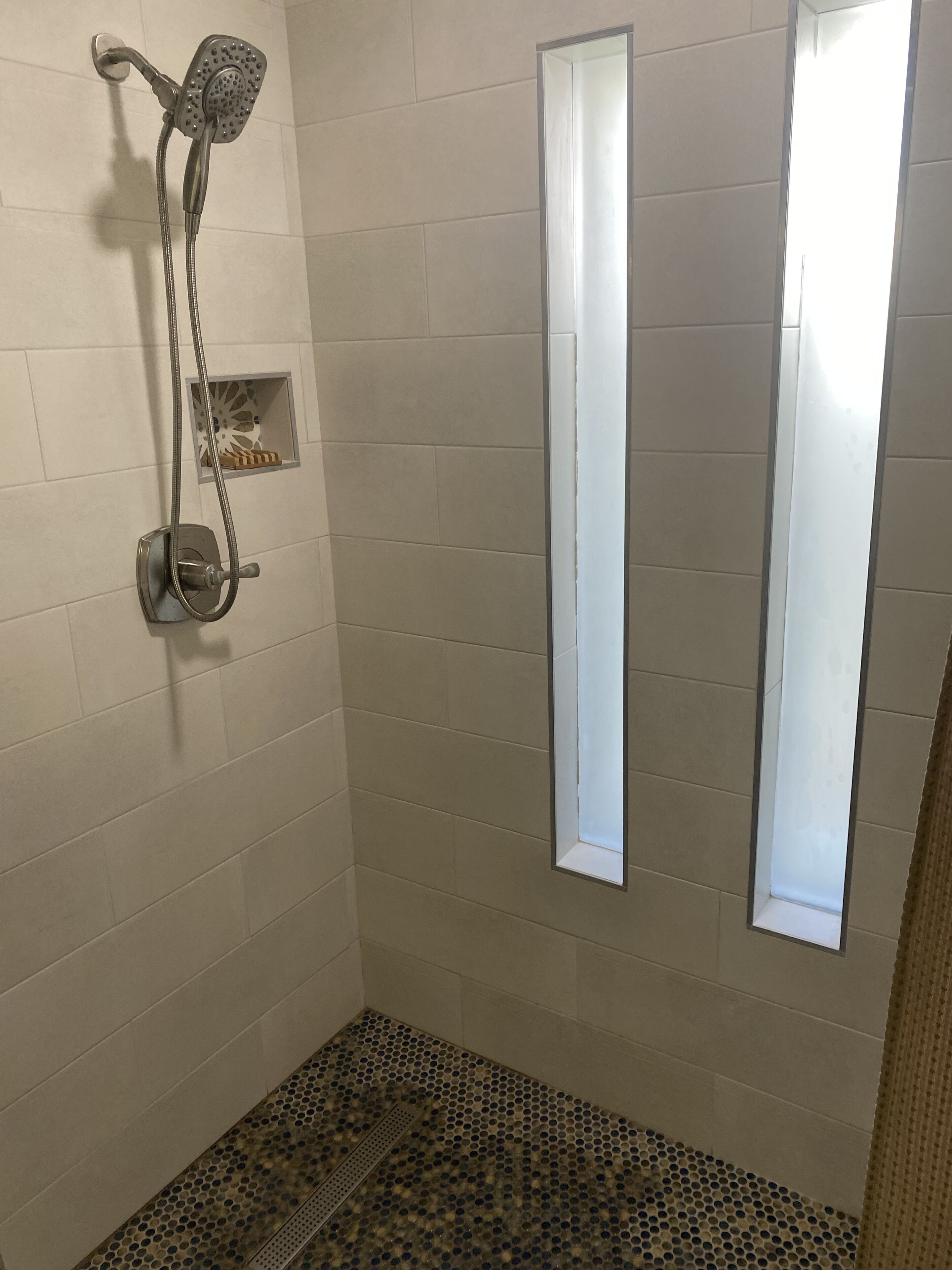 Eine Dusche mit Duschbrause und Wandarmatur.