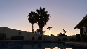 Una piscina con palmeras y un edificio al fondo.