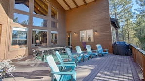 Una terraza de madera con mobiliario exterior y una parrilla.