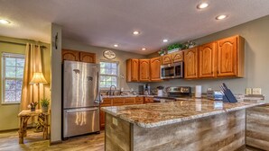 A modern kitchen with wooden cabinets, stainless steel appliances, and a large granite island.
