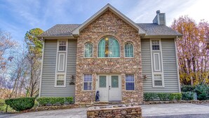 A stone facade house with a central entrance and two side wings.