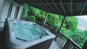 A hot tub on a wooden deck with a view of lush green trees.