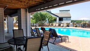 Un espace extérieur abrité comprenant une piscine, des chaises longues et une table.