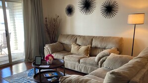Un salon avec un canapé beige, une table basse et des œuvres d’art décoratives accrochées au mur.