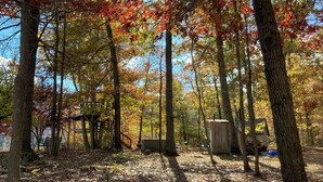 A stone wall in a forested area with trees displaying autumn foliage. - Private mountaintop cabin with hot tub, pool table, and breathtaking views (Great Cacapon)