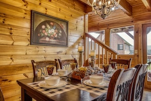 A wooden interior with a dining table set for four, a chandelier, and a staircase leading to an upper level. - September SALE!! American Adventure STARR CREST RESORT, with 3 King beds!! (Sevierville)