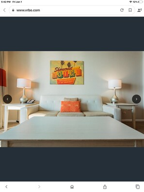 Relax in comfort with a large bed, two nightstands, and a vibrant wall hanging.