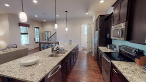 A spacious kitchen with granite countertops, stainless steel appliances, and pendant lighting. - The Seahorse 30A! Golf Cart Included! Sleeps 10! (Santa Rosa Beach)
