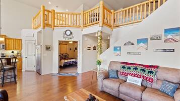 A spacious living area with a wooden staircase, a sofa with decorative pillows, and a coffee table.