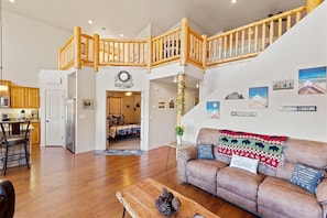 A spacious living area with a wooden staircase, a sofa with decorative pillows, and a coffee table. - Rainbow Lake Cabin · Lakefront with Kayaks · Sleeps 10 · Dogs Welcome (Lakeside)