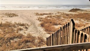 A beach with a wooden fence in the foreground.