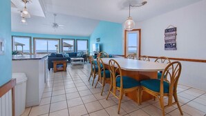 A spacious living area with a dining table, chairs, and a view of the ocean.