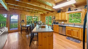 Una cabaña de madera con cocina, comedor y vistas al bosque.