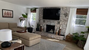 Uma sala de estar com lareira de pedra, televisão de tela plana, sofá e mesa de centro.