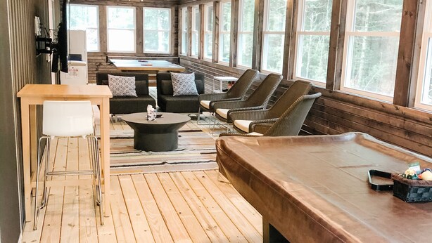 A spacious room with a wooden floor, a long table, and several chairs. There are large windows along one wall, allowing natural light to enter. - Eagle's Nest Guest House II - Less than 2 Miles to Sand Valley - 16 beds! (Nekoosa)