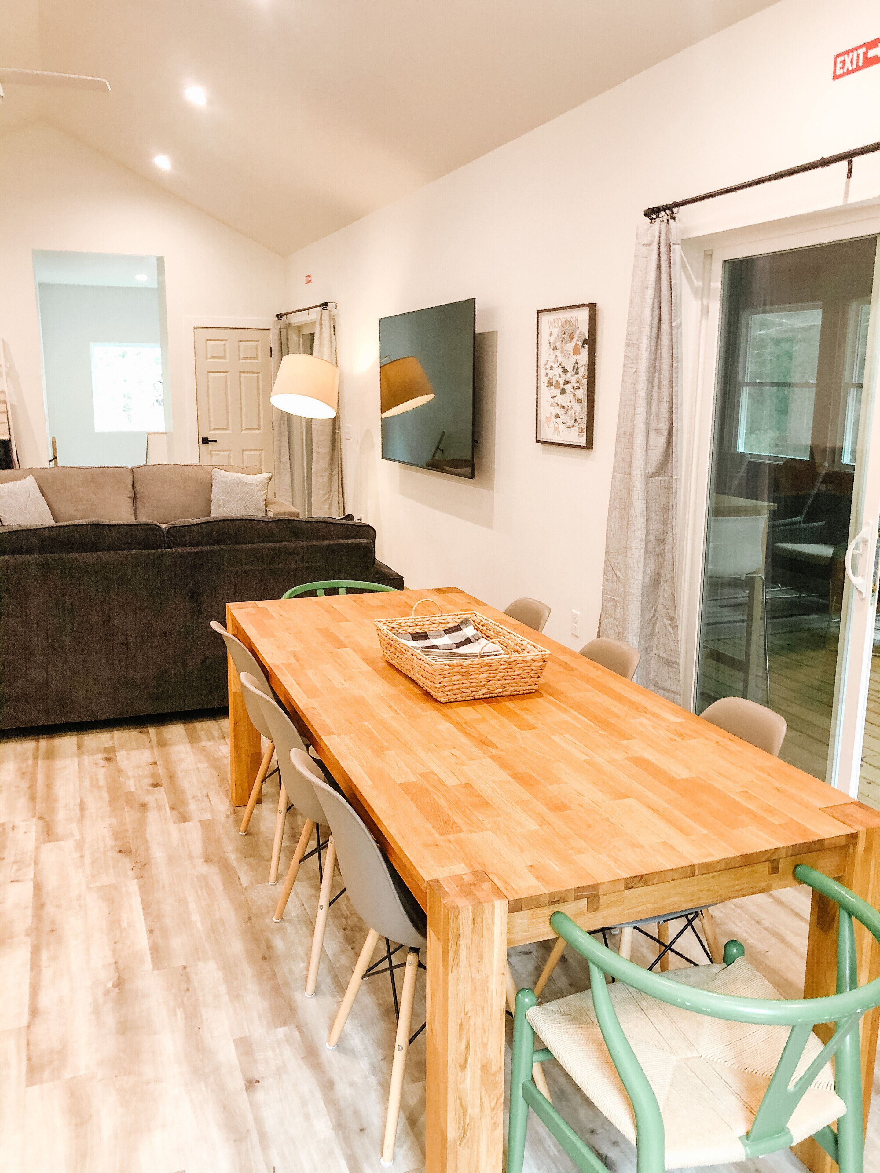 A modern living room with a wooden dining table, a sofa, and a large window.