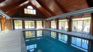 Una piscina interior con techo de madera y ventanas amplias.