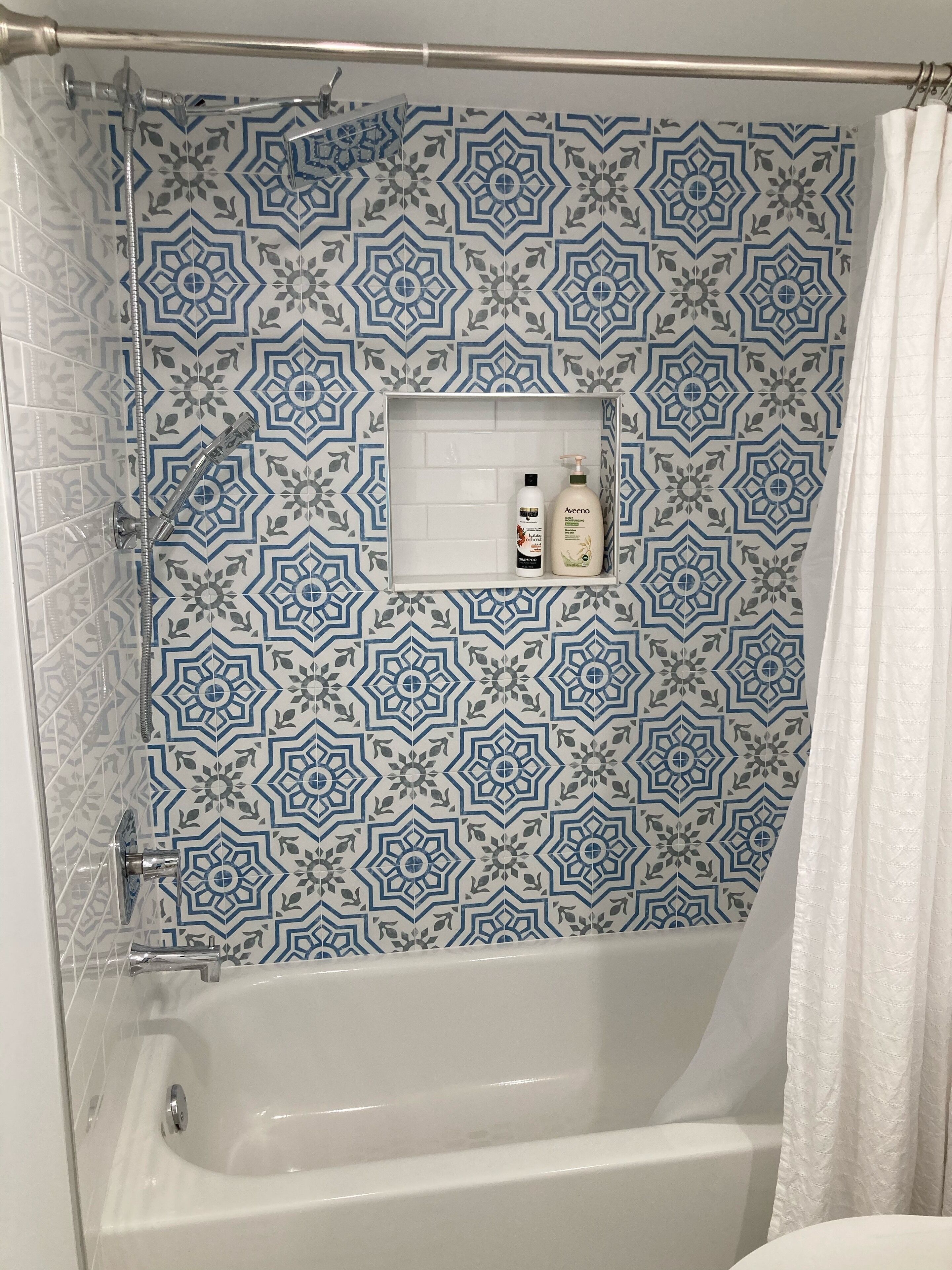 Et badeværelse med bruser, badekar og en hylde med toiletartikler.