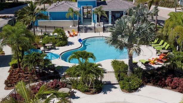 Eine Vogelperspektive eines Resorts mit Schwimmbad, Liegestühlen, Palmen und einer Springbrunnen.
