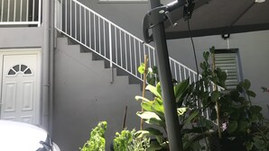 A staircase with white railings leading to a landing with a white door. There are potted plants in the foreground. - Studio for rent (Case-pilote)