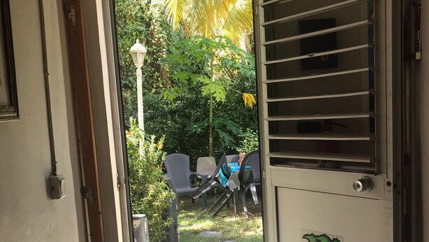 A doorway leading to an outdoor area with a patio, a chair, and a table. - Studio for rent (Case-pilote)