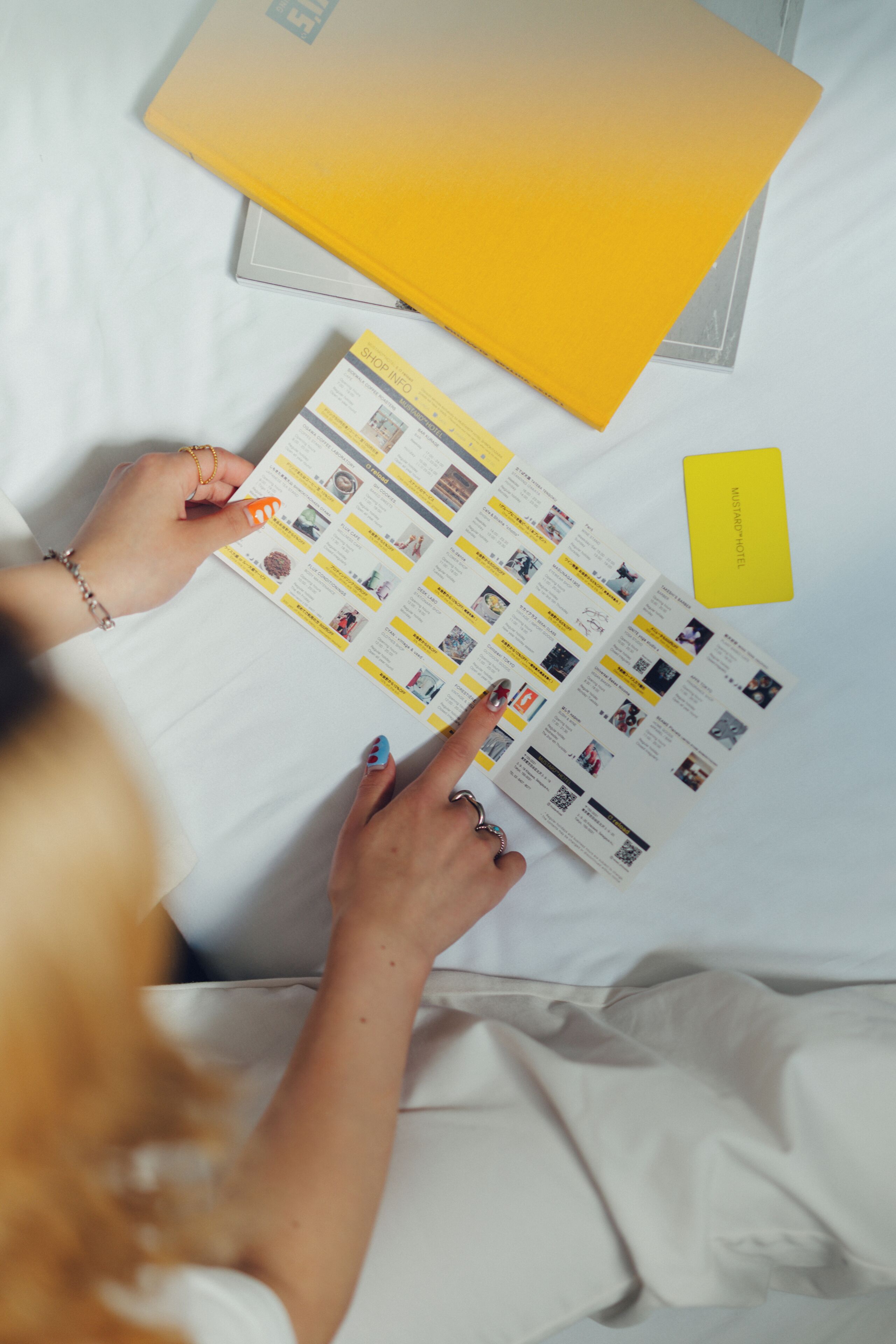 Una persona tiene un depliant con informazioni dell'hotel, una tessera gialla e un portatile su un letto.