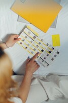 A person holding a brochure with hotel information, a yellow card, and a laptop on a bed.