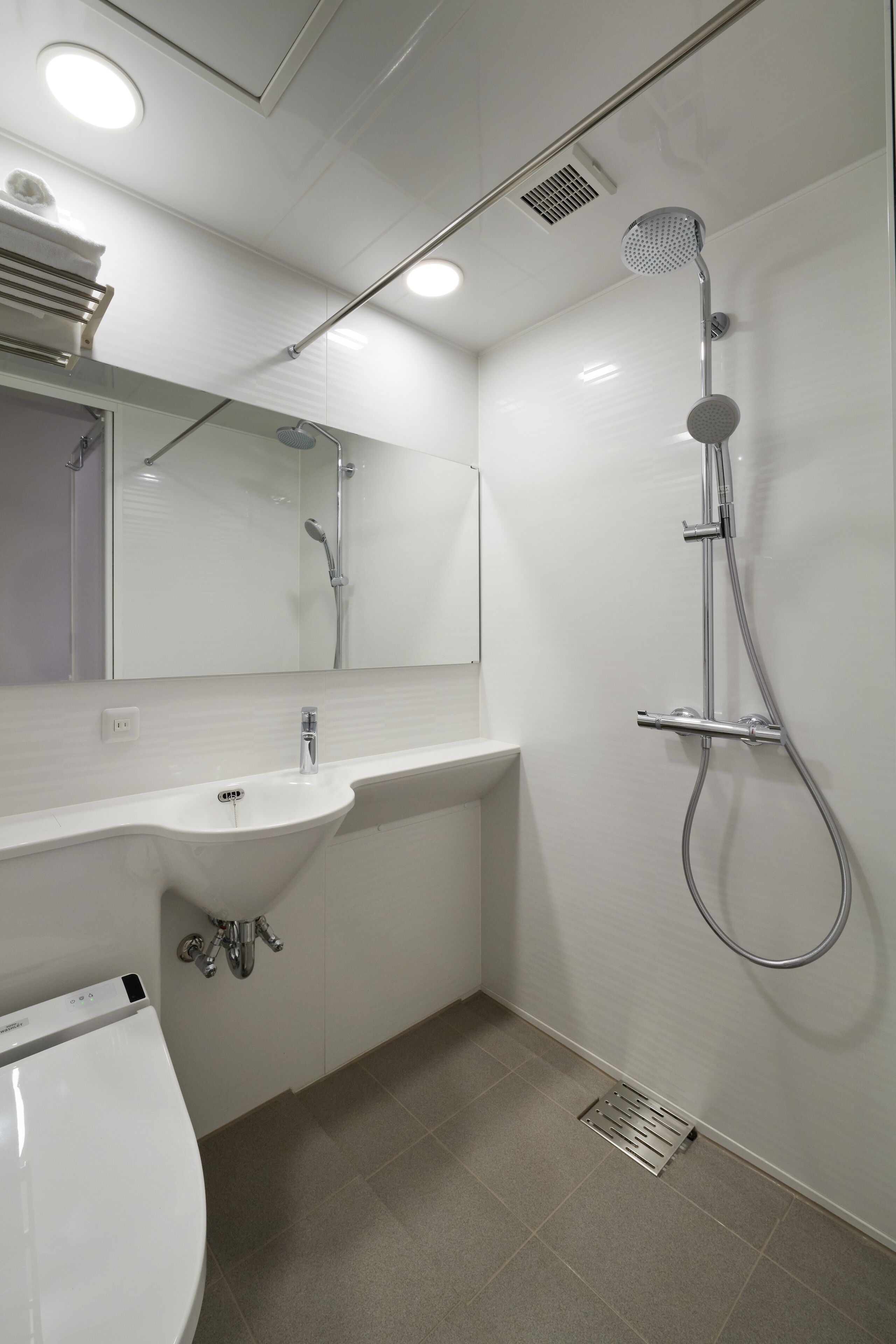 A modern bathroom with a white sink, mirror, and shower.