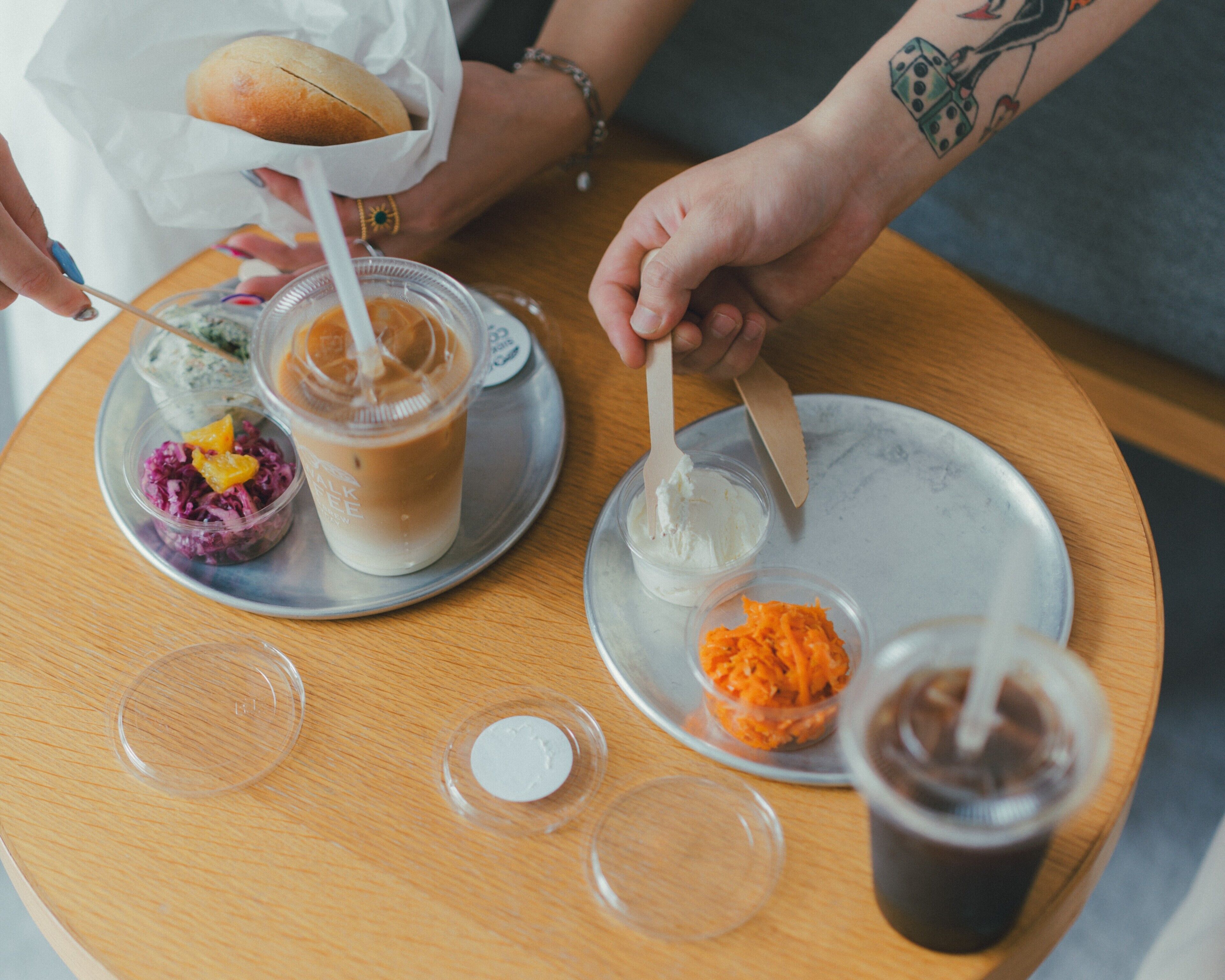 Uma mesa de madeira com uma bebida, um sanduíche e alguns alimentos.