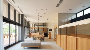 A modern interior with a long dining table, a cushioned bench, and a kitchen area with a visible counter.