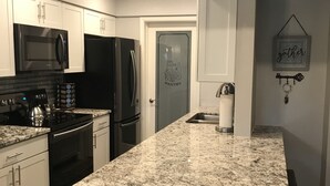 Eine moderne Küche mit weißen Schränken, einer Granitabdeckung, Edelstahlgeräten und Holzboden.