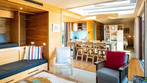 A modern interior with wooden walls, a dining area, and a cozy seating area with a sofa and chairs. - Bach or holiday home, 1 Bedrooms, 2 Bathrooms, (Sleeps 2) (Waimarama)