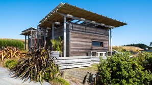 A modern wooden cabin with a covered porch, large windows, and a view of the surrounding landscape. - Bach or holiday home, 1 Bedrooms, 2 Bathrooms, (Sleeps 2) (Waimarama)