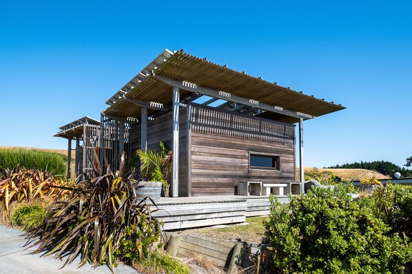 Uma cabana de madeira moderna com varanda coberta, janelas amplas e vista para a paisagem ao redor.