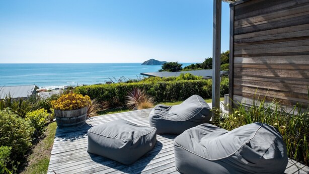 A wooden deck with outdoor seating and a view of the ocean. - Bach or holiday home, 1 Bedrooms, 2 Bathrooms, (Sleeps 2) (Waimarama)