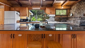 A kitchen with wooden cabinets, a large island, and a stone wall. - Spacious Serene Sanctuary-Minutes to SF and Muir Woods (Mill Valley)
