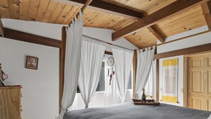 A bedroom with a large bed, wooden ceiling beams, white curtains, and a wooden wardrobe. - Spacious Serene Sanctuary-Minutes to SF and Muir Woods (Mill Valley)