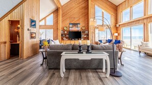 A spacious loft-style room with high ceilings, wooden walls, and large windows.