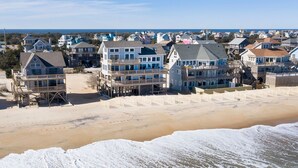 A beachfront property with multiple-story buildings, a sandy beach, and a view of the ocean.