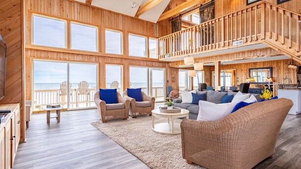 A spacious living area with large windows, a balcony, and a high ceiling.
