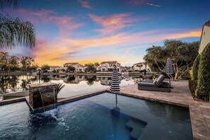 A swimming pool with lounge chairs and umbrellas, surrounded by a landscaped garden and a view of houses in the background. - Ritz Waters at Ocotillo, Heated Pool, 5br/3.5 bath (Chandler)