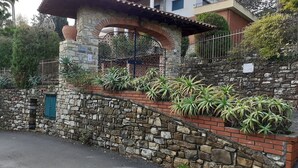 Un muro de piedra con un borde de ladrillo, una puerta verde y una verja de metal.