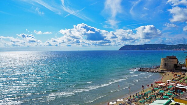 Una playa con cielo despejado, un promontorio rocoso y una torre.