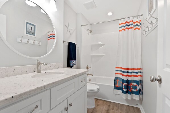 A bathroom with a white sink, a mirror, a toilet, and a shower. - Luxurious & spacious family oceanfront condo w/great views, pools, in popular Cherry Grove (North Myrtle Beach)