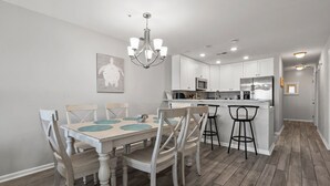 A modern kitchen with white cabinets, a central island with stools, and a chandelier. - Luxurious & spacious family oceanfront condo w/great views, pools, in popular Cherry Grove (North Myrtle Beach)
