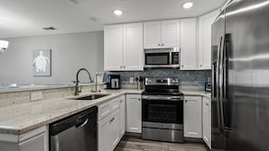 A modern kitchen with white cabinets, stainless steel appliances, and a herringbone tile backsplash. - Luxurious & spacious family oceanfront condo w/great views, pools, in popular Cherry Grove (North Myrtle Beach)