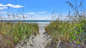 A sandy path leading to the beach, surrounded by tall grasses and plants. - Luxurious & spacious family oceanfront condo w/great views, pools, in popular Cherry Grove (North Myrtle Beach)