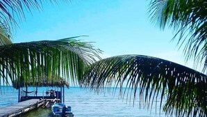 Ein Strand mit einer Anlegestelle, einem Boot und Liegestühlen.
