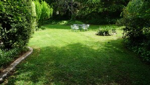 Un jardín bien cuidado con una mesa y sillas preparadas para comidas al aire libre.