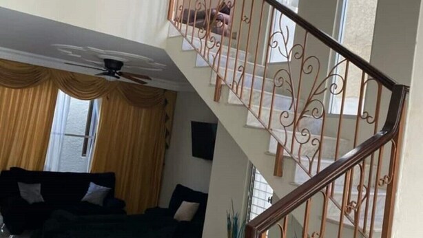 Una escalera con barandales metálicos decorativos y una barandilla de madera que lleva a un piso superior.